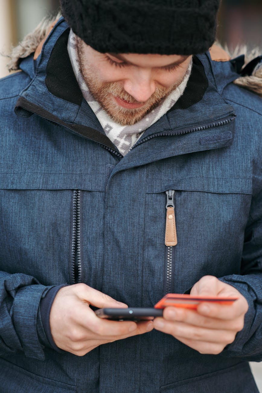 smiling guy making online payment with credit card and mobile phone